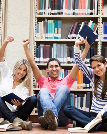 Happy-group-of-students-at-the-library-with-arms-up