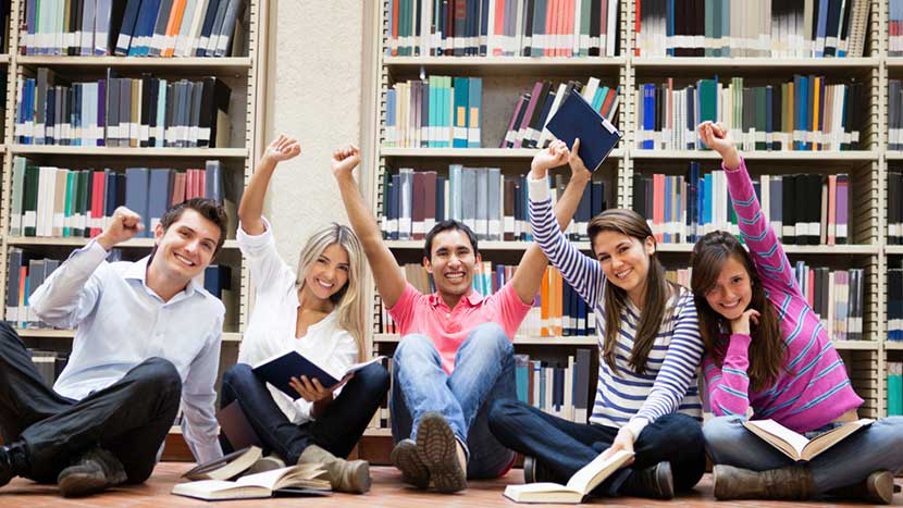 Happy-group-of-students-at-the-library-with-arms-up