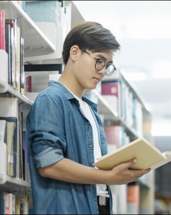 student-looking-at-book-in-library